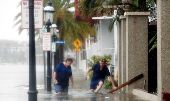 Un hombre y una mujer tratan de abrirse paso en una calle inundada en St. Augustine (AP Photo/John Bazemore)