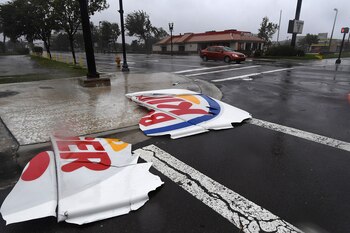 Un auto pasa a metros de un cartel de Burger King que quedó despedazado en Jacksonville (AFP PHOTO / JEWEL SAMAD)