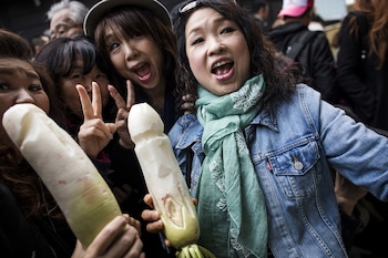 Mujeres comiendo rábano esculpido en forma de pene (AFP)