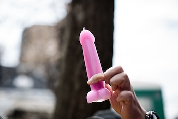 Un hombre sostiene una vela en forma de pene (AFP)