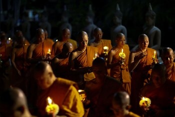 Monjes budistas cargan velas mientras