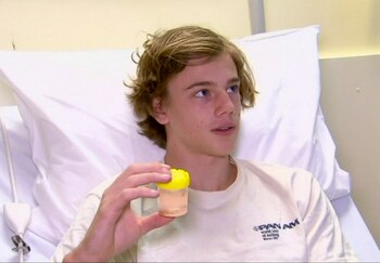 El adolescente Sam Kanizay con una muestra de las criaturas marinas que le mordieron los pies (Australia Pool via AP)