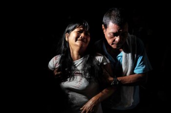 Néstor Hilbano consuela a su mujer, Alma, después de que ambos hayan visto el cadáver de su hijo en una bolsa en un callejón oscuro de Tatalon. Richard Hilbano, de 32 años, fue abatido por la policía en una redada antidrogas. Los agentes declararon que Richard estaba fumando marihuana con otras tres personas y los mataron a todos. JES AZNAR