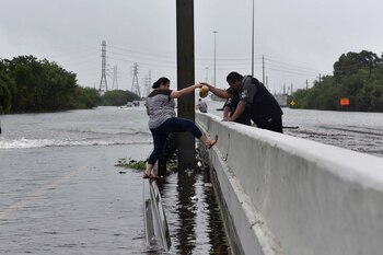 Un policía ayuda a una mujer a evitar caer al agua (Reuters)