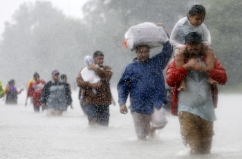 Residentes caminan en el agua en Beaumont Place, Houston (Reuters)