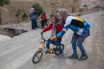 Zakia Mohammadhi, de 23 años de edad, empuja a su hermana menor, Honey, de 7 años de edad en bicicleta hasta su casa, que se encuentra en un camino de tierra hasta una colina que puede ser todo un reto para un niño. (Paula Bronstein)