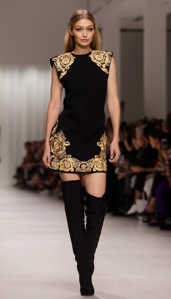 Gigi Hadid formó parte de la pasarela con un estilo clásico de Versace, al tener estampados dorados bordados con hilo, un vestido negro y botas altas. (AP Photo/Luca Bruno)