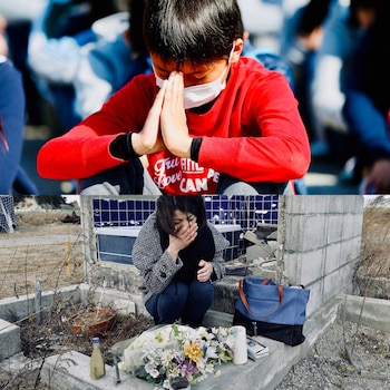 Un niño japonés ora tras un terremoto mientras que una mujer despide a una de las víctimas de la catástrofe que tuvo lugar en marzo de 2011