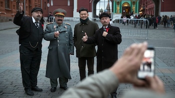 Sergei Soloviev y otros imitadores se fotografían junto a un turista en la plaza roja (AP Photo/Pavel Golovkin)