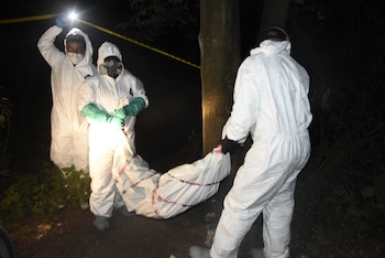 Investigadores forenses trasladan el cuerpo