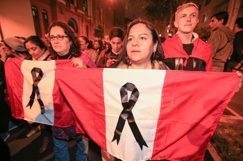 Manifestantes sostienen banderas peruanas con