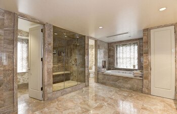El imponente baño con una bañera, una ducha y un pequeño Spa en la que predomina el marmol
