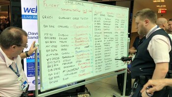 Un empleado del aeropuerto, anotando el estado de los vuelos en una pizarra