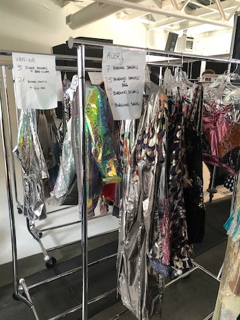 Percheros con nombre de la modelo y vestido que lucirá en al pasarela, calzado y accesorio para completar el look.