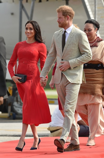 El príncipe Harry y la duquesa de Sussex llegaron al aeropuerto de Fua’amotu en Tonga el 25 de octubre de 2018. En esta ocasión optó por un deslumbrante vestido rojo fuego de Self Portrait (AFP)