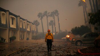 Un bombero camina por zona aledaña que aún no ha sido devastada por el incendio. (Reuters)