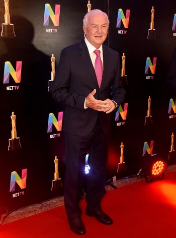 Fernando Niembro con traje negro, zapatos de cuero marrón y el detalle de color, su corbata rosa con lunares