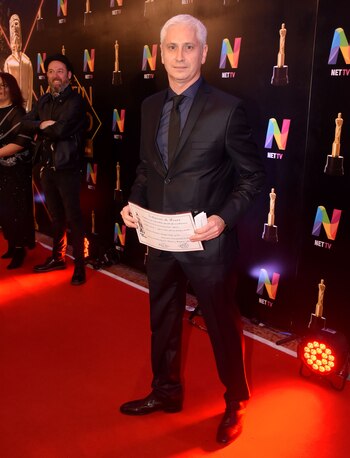 Juan Dinatale con esmoquin negro, zapatos de cuero, camisa azul noche y corbata slim negra