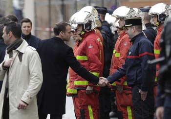 Emmanuel Macron, presidente de Francia, saluda a un bombero durante la visita al Arco del Triunfo. (VAN DER HASSELT / AFP)