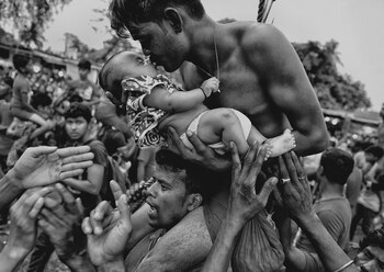 Un hombre hindú besa a un recién nacido durante el festival Charak Puja, en la India