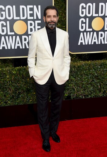 Tony Shalhoub con saco blanco y pantalón negro