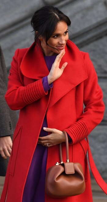 La duquesa de Sussex, lució su embarazo en la visita oficial al Birkenhead junto al príncipe Harry, y optó por un vestido violeta low cost de 50 dólares y un tapado rojo de Sentaler. Su look color block recordó mucho a dos outfits del mismo tono usados por la mamá del príncipe Harry (AFP)
