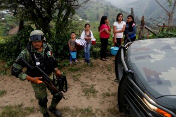 Un soldado se para cerca de los residentes cuando llega al área donde encontraron una plantación ilegal de opio en la Sierra Madre del Sur, en el estado sureño de Guerrero, México, el 24 de agosto de 2018.