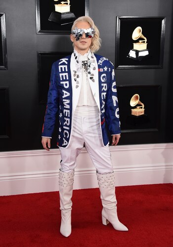Ricky Rebel en total white, con pantalón, camisa y botas con tachas, el cantante llevó la política nuevamente a la alfombra roja de los Grammy con un mensaje para Trump