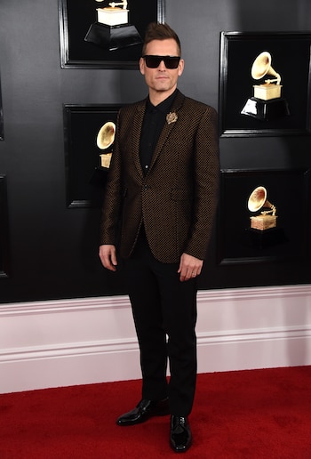 Kaskade apostó a un esmoquin negro con camisa, pantalón y zapatos acharolados negros. El distintivo fashionista, el saco cuadrillé dorado y prendedor. Completó el look con gafas de sol oscuras