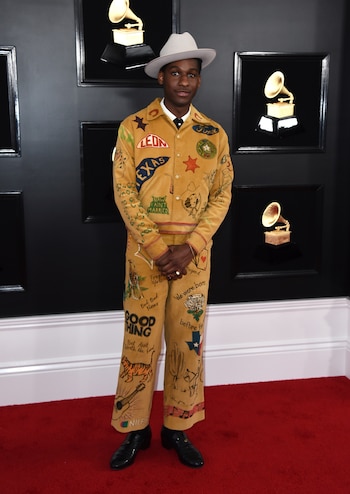 Leon Bridges lució en la red carpet un traje de corderoy en color mostaza con apliques, pintado y bordado con frases y dibujos. Lo completó con botas de cuero negra y un sombrero de baby alpaca en gris