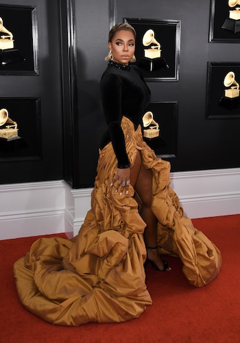 Ashanti apostó a un vestido que combinó la tendencia de puffer (inflados) con el chiffón. Con un maxi tajo, la falda vaporosa en color mostaza y el torso negro de mangas largas con detalles de strass en puños y cuello polera