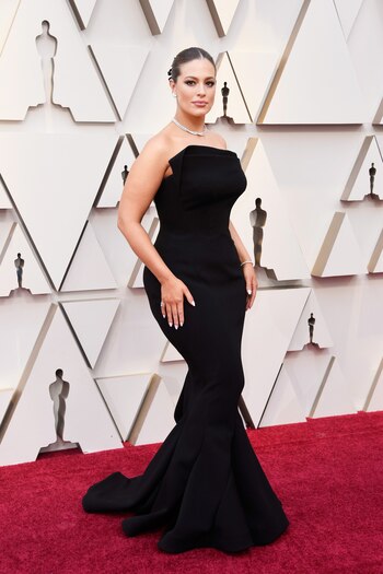 Ashley Graham, la modelo plus size, apostó a un vestido strapless sirena en negro con cola. De joyas, una pulsera de brillantes, anillos, gargantilla y pendientes. Maquillaje smokey eye y labios nude. Para el peinado, eligió un recogido tirante