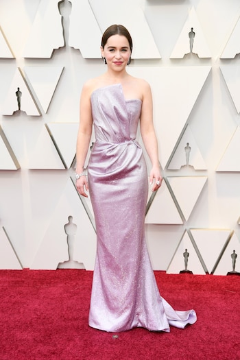 Emilia Clarke by Balmain. Un vestido sirena en color lila de paillettes drapeado en la cintura con cola y de escote irregular. Completó su look con brazalete de brillantes, anillo de piedra y aros colgantes. Su beauty look, labios coral y su nuevo corte de pelo, bob hair