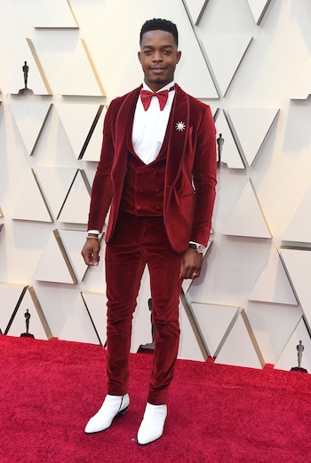 Stephan James con esmoquin achupinado en chiffón rojo de tres piezas by Etro y booties de cuero blancas