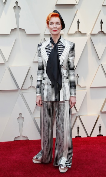 Sandy Powell impactó con un look masculino rayado en blanco, gris y negro. Completó el look con un foulard, los clásicos zapatos de Stella McCartney y boina negra