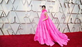 Gemma Chan eligió al color fucsia para los Oscars. Un maxi vestido línea A sin mangas con cuello cisne de volados by Valentino, joyas Bulgari y zapatos Jimmy Choo