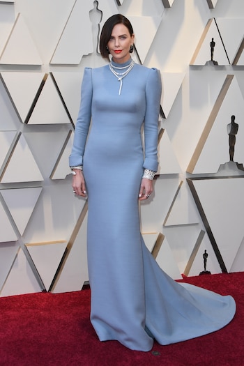 Charlize Theron enfundada en un diseño de Dior en color celeste con espalda al descubierto, cola, hombreras y cuello polera. Completó su look con anillos, brazaletes de brillantes y gargantillas de Bulgari. Impactó con su beuty look: maquillaje con labios anaranjados y corte de cabello bob