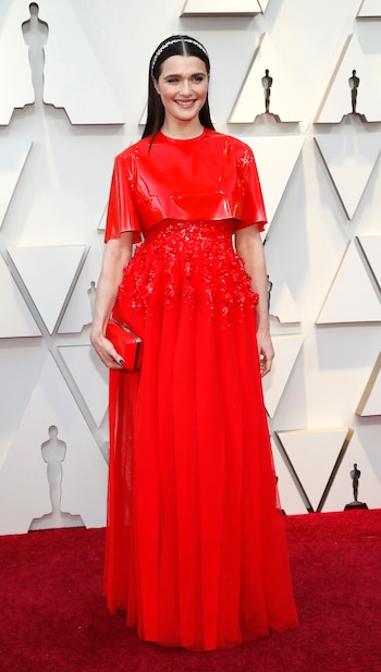 Rachel Weisz apostó al total red look. Con superposición de prendas, un top de vinilo y vestido plisado bordado, completó el look con clutch rígido y vincha de laureles plateados