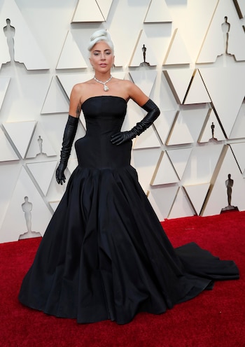 Lady Gaga, la más esperada de la noche, impactó con su vestido negro encorsetado hasta la cadera con falda volptuosa que completó con guantes de cuero y un gran collar con piedra. Eligió para su beauty look un cabello recogido, smokey eye en metalizados