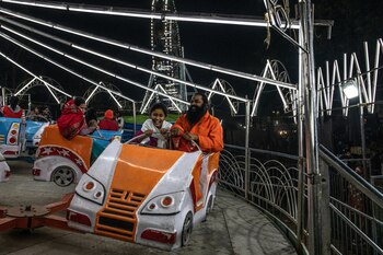 Un hombre santo y una niña disfrutaban de una de las atracciones mecánicas del festival. (The New York Times)