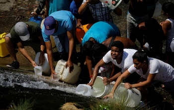 En una medida desesperada, un grupo de personas bajó este lunes al canal del infesto río Guaire, en Caracas, para surtirse del líquido en una bocatoma ubicada a un costado
