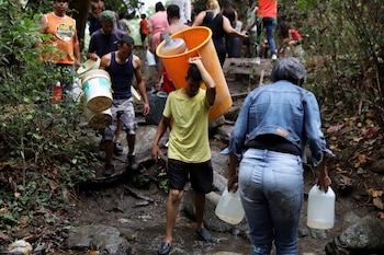 Las personas cargan recipientes para llenar con agua de un río en Caracas, Venezuela, 31 de marzo de 2019. (REUTERS)