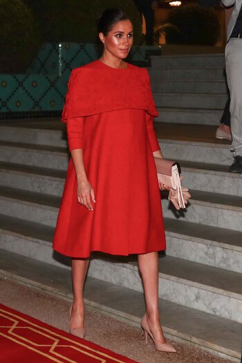 Meghan comenzó su gira real marroquí con un vestido rojo de capa de Valentino para su llegada al aeropuerto de Casablanca. La duquesa combinó el look con tacones y guantes color nude y un clutch Valentino Garvani (AP)