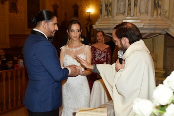 El cura bendiciendo los anillos de matrimonio de Ariel Puchetta y Camila Minoldo