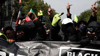 Manifestantes enmascarados asisten a una