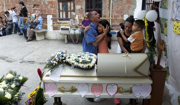 Los padres de una de las víctimas lloran ante el féretro (AP)