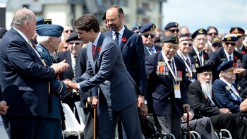 El primer ministro de Canadá, Justin Trudeau, seguido por su par frances Edouard Philippe, honrando a los veteranos canadienses en Courseulles-sur-Mer, Normandía (AFP)