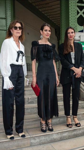 Carolina de Mónaco y Charlotte Casiraghi eligierion vestirse de Chanel para la ocasión. Carolina optó por una camisa blanca con lazada en color negro y mangas plisadas que combinó con un pantalón satinado negro, mientras que su hija eligió un bonito vestido negro con escote cuadrado, mangas de gasa transparente, falda con aberturas y lazada en el escote. Las acompañó Tatiana Santo Domingo.