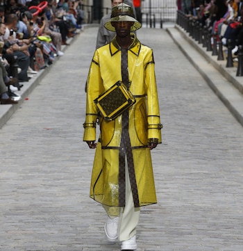 Uno de los protagonistas de la colección de Louis Vuitton fue el impermeable con el logotipo de la marca. De corte midi y con el sombrero haciendo juego, el look lo completó una crossbody en amarillo con el monogram en marrón