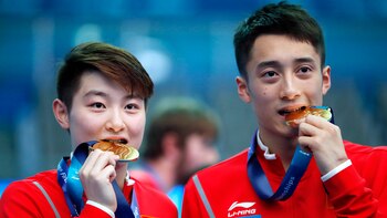 Los chinos Si Yajie y Lian Junjie “prueban” sus medallas de oro